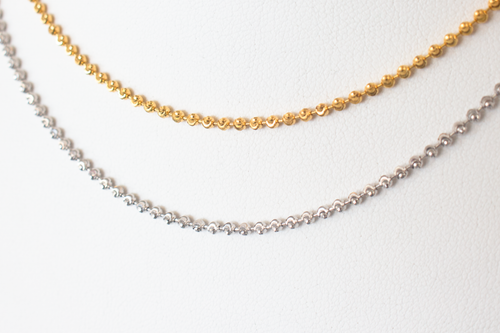Cassie Genuine 14 karat gold diamond cut beaded choker in yellow gold and white gold laid flat on a white background.