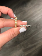Load image into Gallery viewer, Two Diamond Deco Stackable Ring in 14k yellow and white Golds pinched between the thumb and forefinger of a hand on a wooden background.