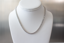 Load image into Gallery viewer, 11 Carat Diamond Tennis Necklace in white gold hanging on a white bust.
