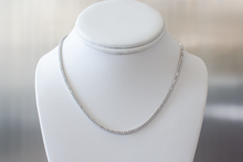 Load image into Gallery viewer, 5 Carat Diamond Tennis Necklace in white gold hanging on a white bust on a light gray background.
