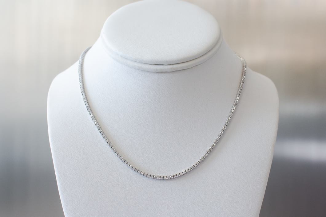 5 Carat Diamond Tennis Necklace in white gold hanging on a white bust on a light gray background.