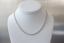 Load image into Gallery viewer, 6.25 Carat Diamond Tennis Necklace in white gold hanging on a white bust on a light gray background.
