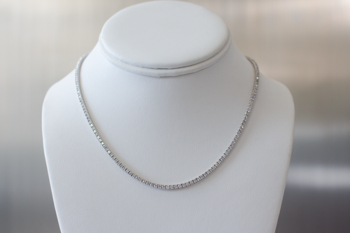 6.25 Carat Diamond Tennis Necklace in white gold hanging on a white bust on a light gray background.