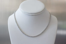 Load image into Gallery viewer, 7.5 Carat Diamond Tennis Necklace in white gold hanging on a white bust on a light gray background.
