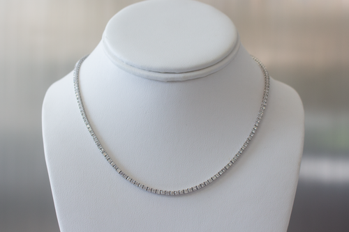 7.5 Carat Diamond Tennis Necklace in white gold hanging on a white bust on a light gray background.