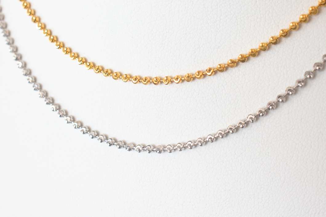 Cassie Genuine 14 karat gold diamond cut beaded choker in yellow gold and white gold laid flat on a white background.