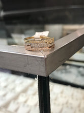 Load image into Gallery viewer, Three Diamond Offset Stackable Ring in 14k yellow, white and rose Gold stacked on atop one another resting on the corner of a steel table.
