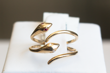 Load image into Gallery viewer, Two Snake Wrap 14k Yellow Gold Rings with ruby and diamond eyes stacked on a ring stand on a white background.
