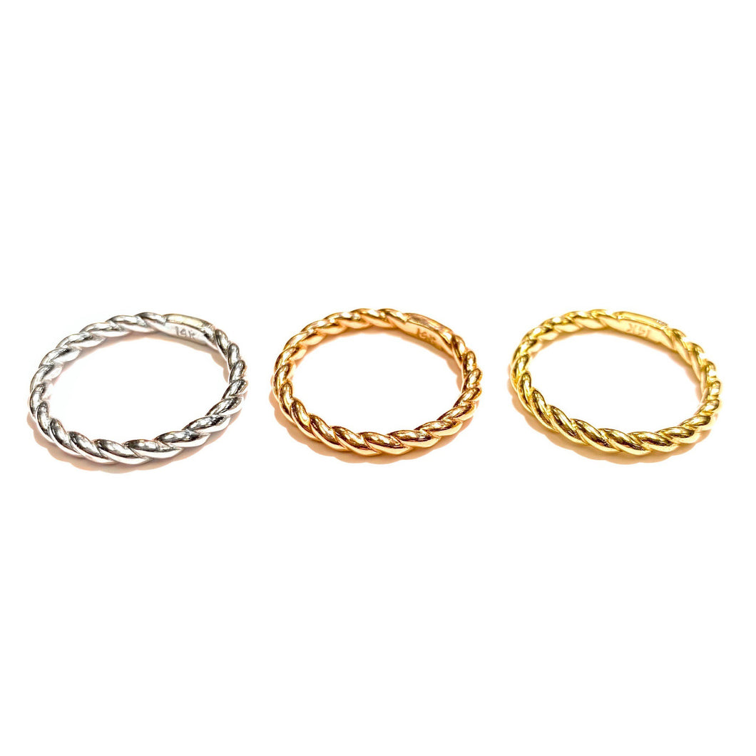 Three Twist Rings in 14k white, rose and yellow Gold laid flat on a white background.